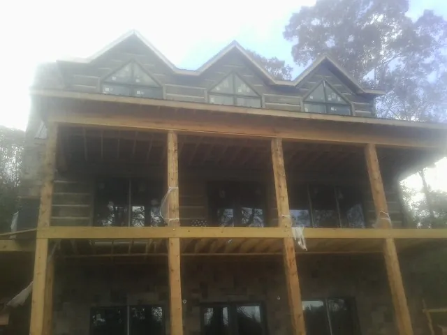 Dormers and porch framing on a large log home under construction — Roof Coating work by our crew in Rushville